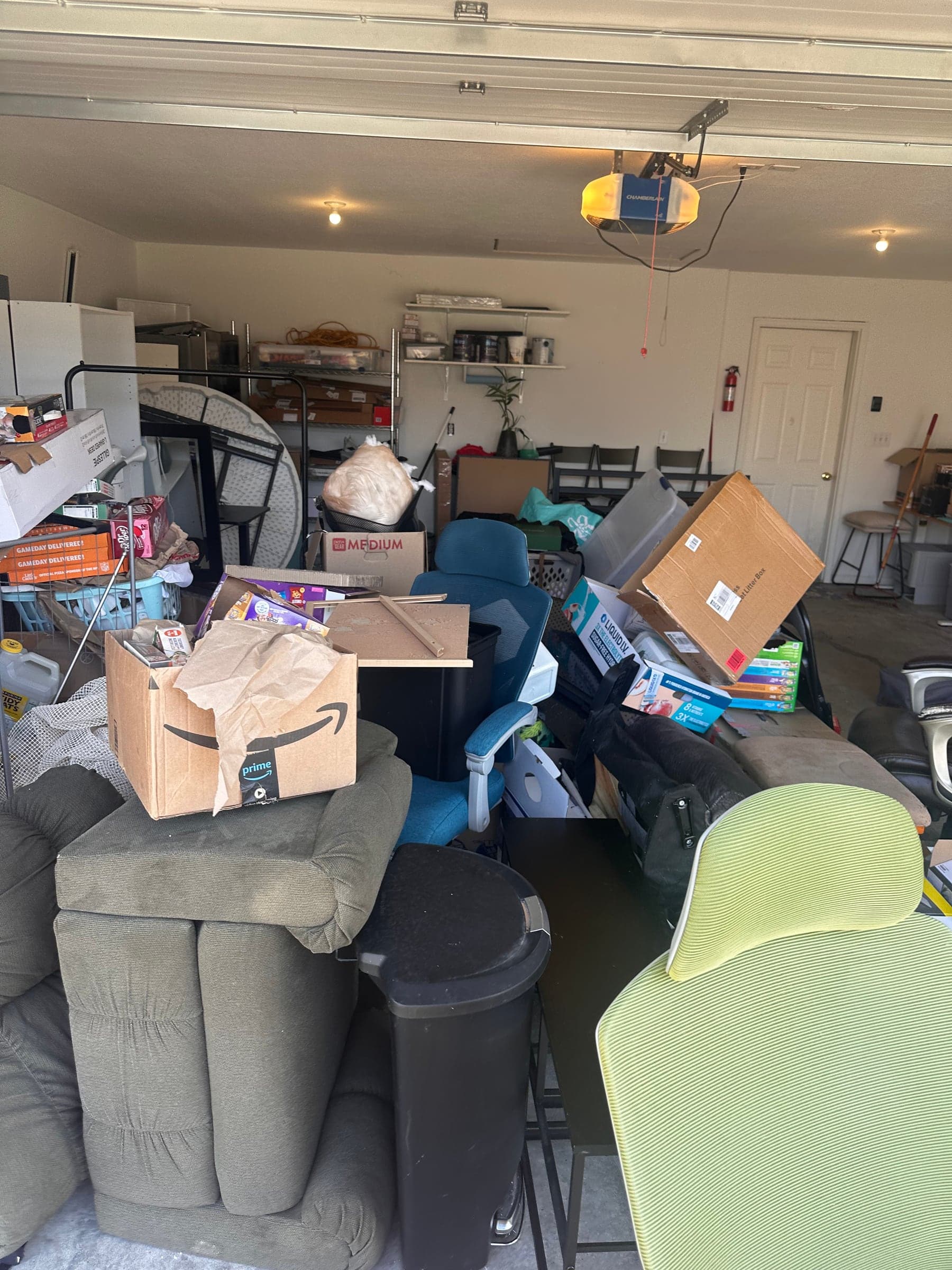 A garage stacked with a couch, chairs, and boxes left after a move