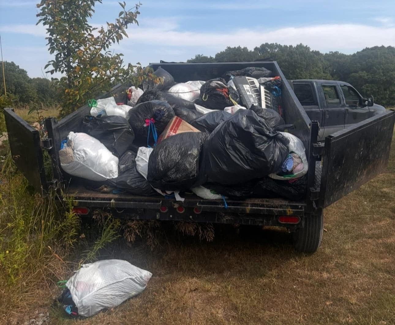 Dump trailer loaded with bagged household junk behind the truck